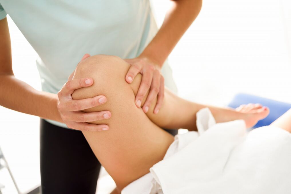 The specialist makes therapeutic massage with knee arthrosis